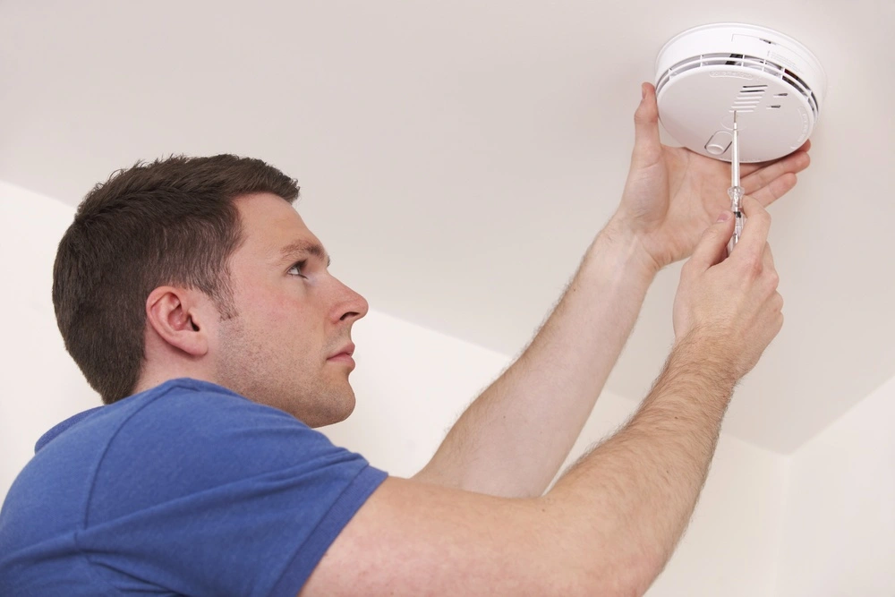 technician installing smoke alarm detector