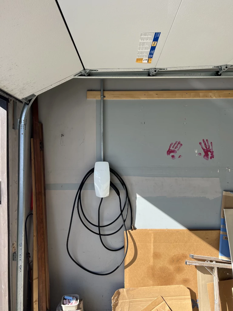 tesla ev charger next to an open garage door